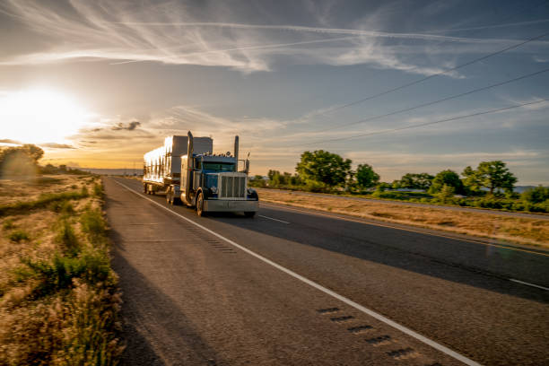 long haul semi truck speeding down a four lane highway in a beautiful sunset - four lane highway stock-fotos und bilder