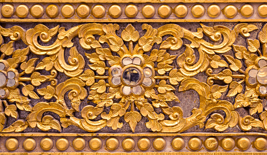 Pattern of gold flower carved on stucco design of native wall, Thai style in temple