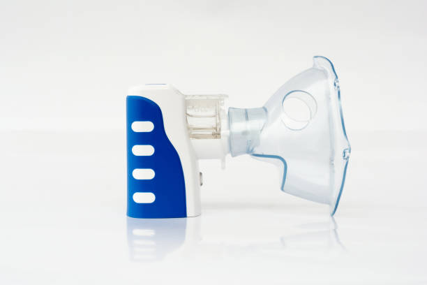Closeup small portable nebulizer inhaler on white reflection background, Medical healthcare concept. Closeup small portable nebulizer inhaler on white reflection background, Medical healthcare concept. pediatric nebulizer mask stock pictures, royalty-free photos & images