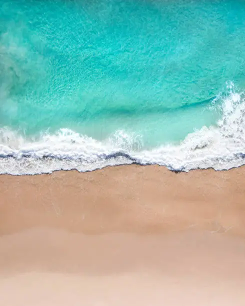 Photo of Aerial top shot of a beach with nice sand, blue turquoise water and tropical vibe