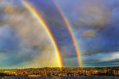 double rainbows over city at sunset