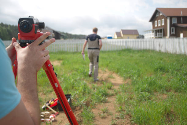 Two surveyors measuring land with theodolite, focus in the foreground