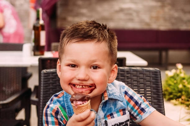 istock child eats chocolate ice cream. little boy covered in ice cream. 1153578299
