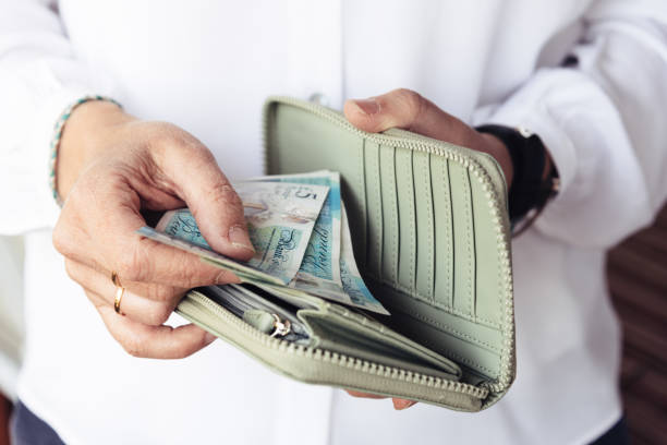Woman taking out pounds from her pocket wallet Close up of hand of woman taking out pounds from her purse british currency stock pictures, royalty-free photos & images