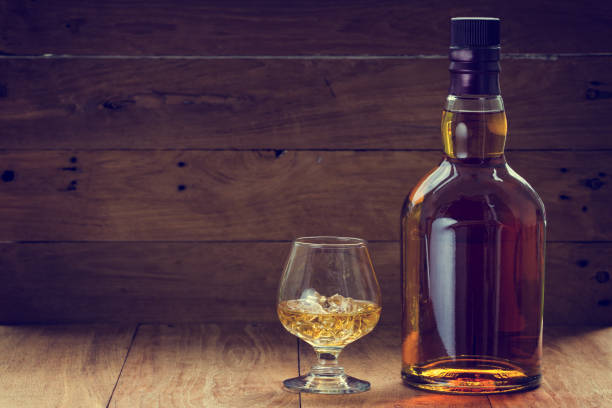 butelka i szklanka whisky na drewnianym tle wykonanym w odcieniach vintage - isolated on white bottle alcohol alcoholism zdjęcia i obrazy z banku zdjęć