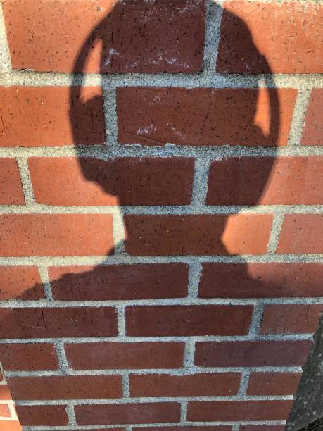 istock M Man’s shadow with headphones on over retro style red brick patterned wall 1153582486