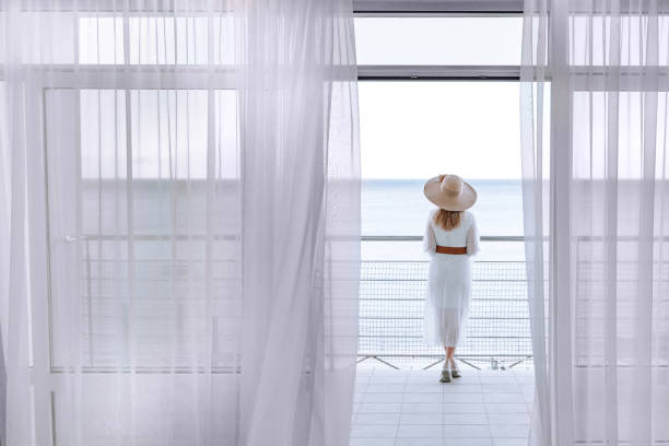 una donna che si gode la vista sul mare con una splendida vista dalla terrazza. - balcony women patio coffee foto e immagini stock