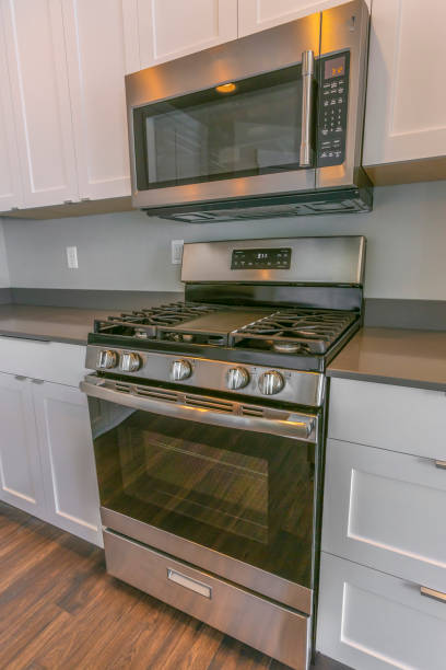 istock Range and wall mounted microwave inside the kitchen with brown wooden floor 1153587288