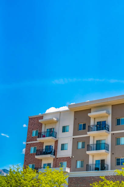 istock Lush trees in front of a building with red brick wall and small balconies 1153590978
