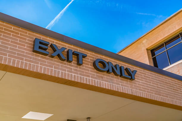 istock Exit only sign on the exterior brick wall of a building with shiny window 1153591022