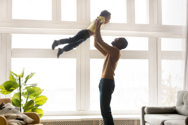 Happy african father lifting up in air little son
