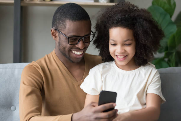 istock African father mixed race daughter having fun use smart phone 1153592568