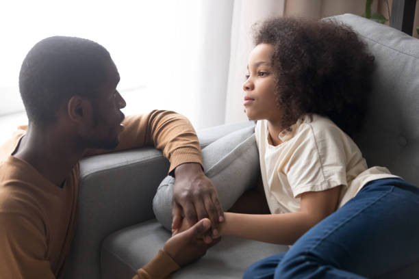 istock Father hold hand little daughter lying on sofa feels unwell 1153592592