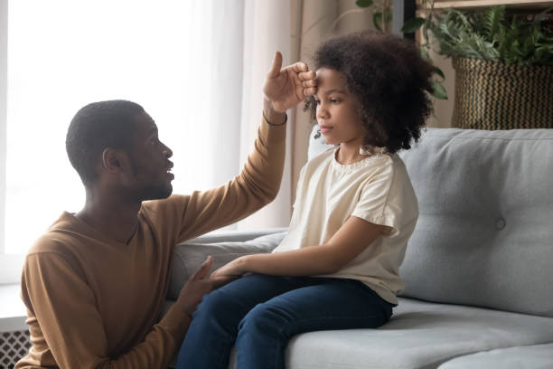 Worried father touch forehead of unhealthy daughter sitting on sofa Worried dad father check temperature touch forehead of biracial unhealthy schoolgirl daughter sitting on sofa at home. Ill sick kid girl, parenting support, care love, treatment and healthcare concept young hot stock pictures, royalty-free photos & images