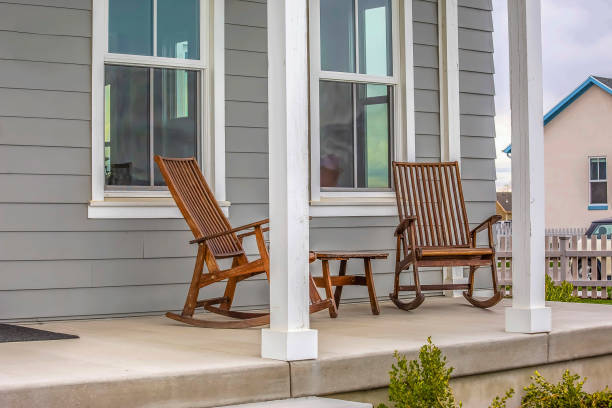istock Front porch of a house with brown rocking chairs and rectangular white pillars 1153594755