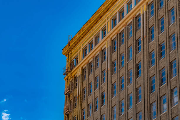 Exterior of a modern building with outdoor stairs for emergency exit. The vibrant blue sky is reflected on the rectangular glass windows of the building.