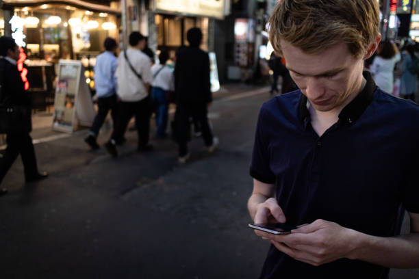istock A handsome man looking at his phone on a Tokyo street 1153596344