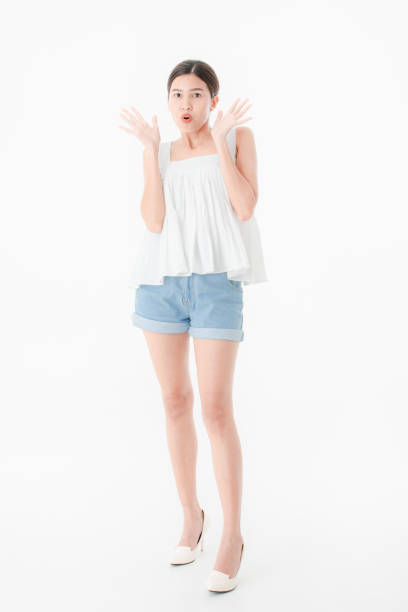 Full length, portrait of young beautiful, attractive Asian woman in casual summer outfits, denim shorts and loose tank top, high heel, standing, posing surprise expression, on isolated white background