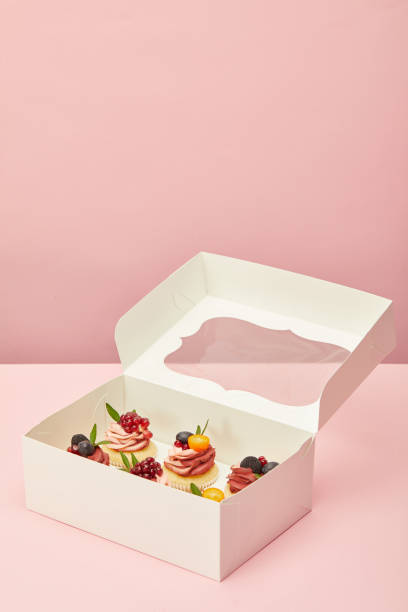 white box with sweet cupcakes on pink surface