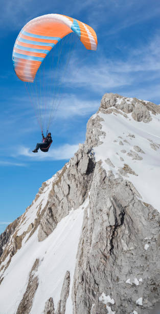 Person is gliding through the sky with a colorful parachute, enjoying the freedom of paragliding, cloudy sky background. Sagres, Portugal - December 29, 2023.