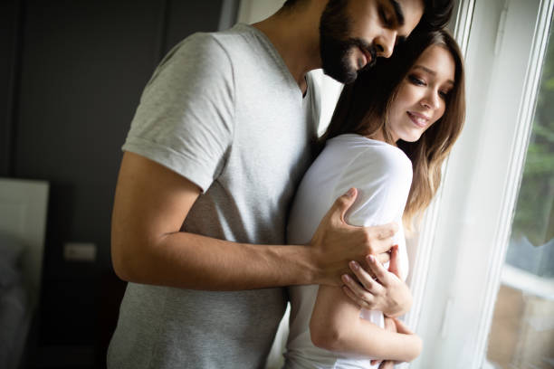 istock Beautiful couple is smiling and hugging while spending time together in bedroom 1153600067