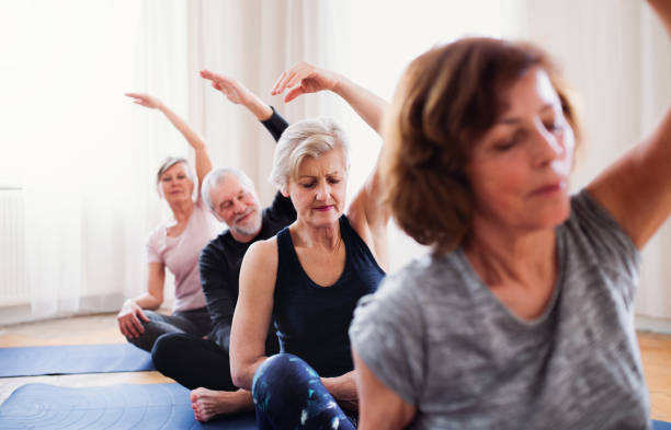 group of senior people doing yoga exercise in community center club. - senior adult relaxation exercise healthy lifestyle exercising imagens e fotografias de stock