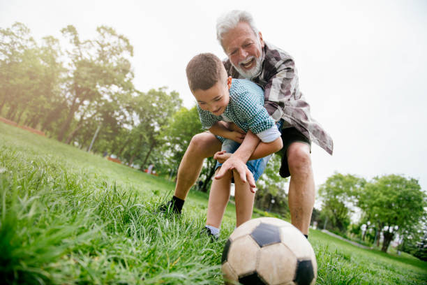 おじいちゃんと孫は楽しんで、サッカー - helmet child padding football helmet ストックフォトと画像