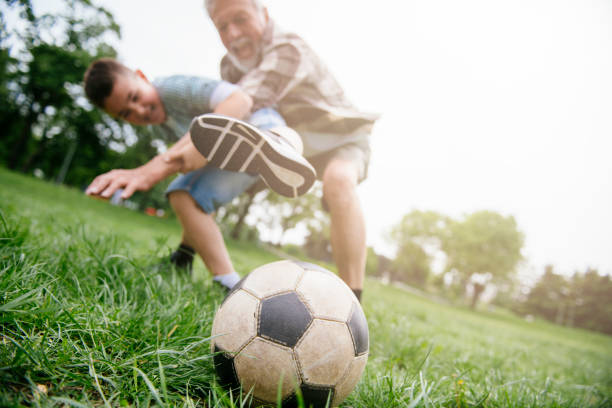 おじいちゃんと孫は楽しんで、サッカー - helmet child padding football helmet ストックフォトと画像