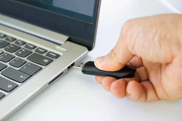 istock hand man connect flash drive to USB port plug-in computer laptop 1153611635