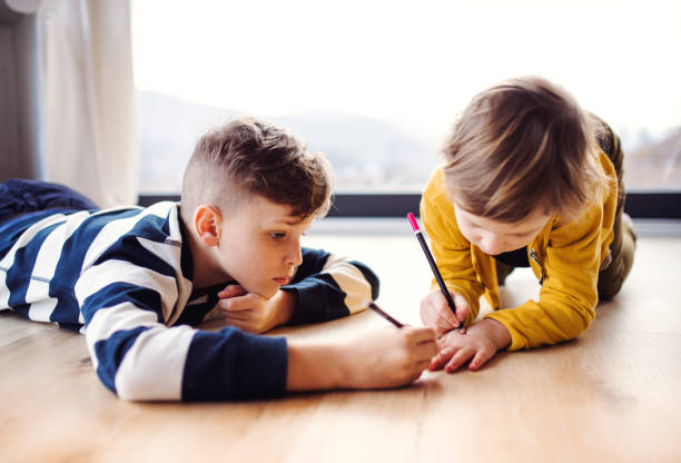 istock Two happy children lying on floor indoors at home, drawing. 1153612845