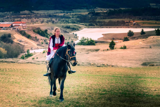 Bachevo, Bulgaria - March 16, 2019: Horse Easter or the day of Todor in Bulgaria, lady in traditional bulgarian clothing riding a horse in the mountains