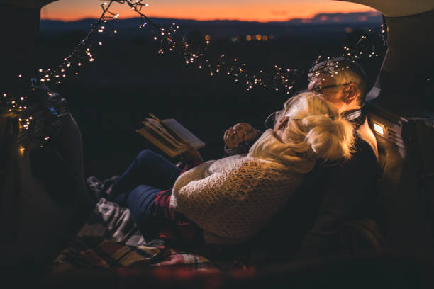 istock Senior couple sit in open car trunk and reading a book 1153620628