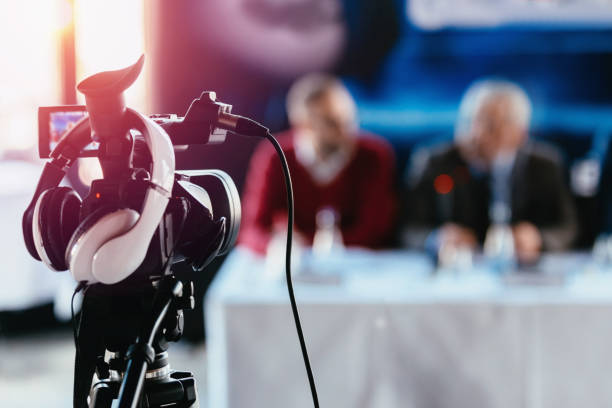 istock Close-Up Of Camera With Headphone Against People Sitting On Table 1153625343