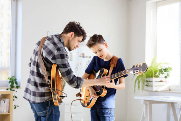 Teenage boy learning electric guitar from trainer