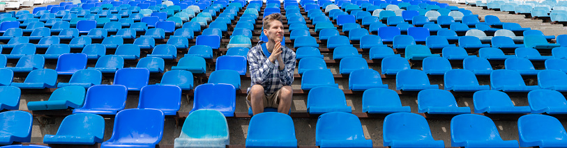lonely man on the empty stadium seat cheering for the team, one man army concept