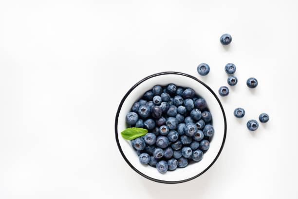 bleuets frais dans le bol sur le fond blanc - healthy eating breakfast ripe fruit photos et images de collection