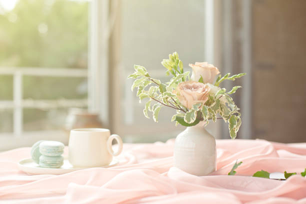 istock French blue macaroon plate and coffee cup standing on a wooden table with a pink tablecloth white vase with flowers roses and greens 1153631230