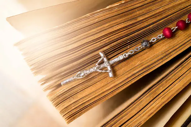 Cross on the Bible on a wooden background. Holy book.