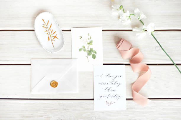 istock Wedding invitation as a decorated letter on a white tablecloth with a flower arrangement. 1153632568