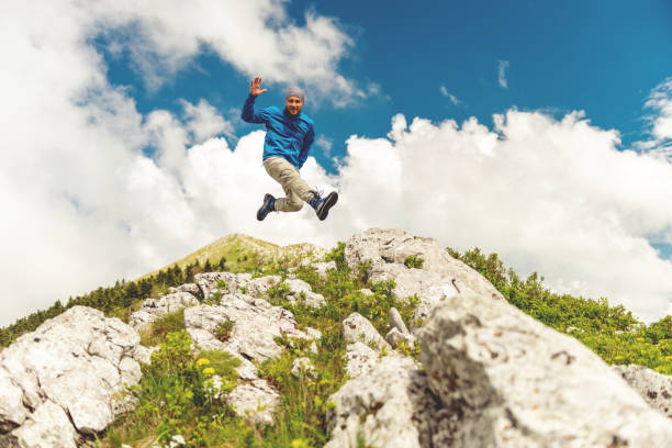 istock Male hiker jumping on a rocky mountain 1153633460