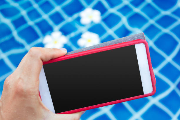 istock Smartphone with black screen near pool. Vacation concept 1153641313