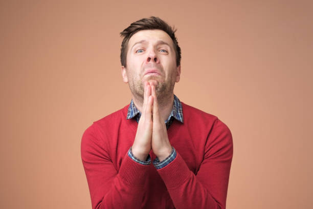 istock Desperate young man showing clasped hands, sorry for mistake 1153641570