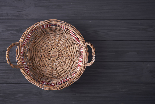Top view of empty wicker basket on grey wooden planks