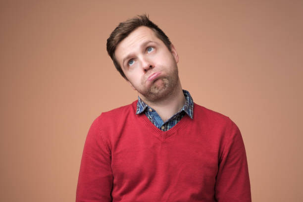 istock man in red sweater puffing his cheeks, feeling fed up as heis tired. 1153642805