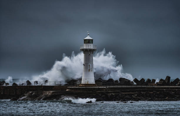 Wollongong Breakwater Lighthouse in the Storm The Breakwater Lighthouse of Wollongong with a wave breaking behind it during a storm groyne stock pictures, royalty-free photos & images