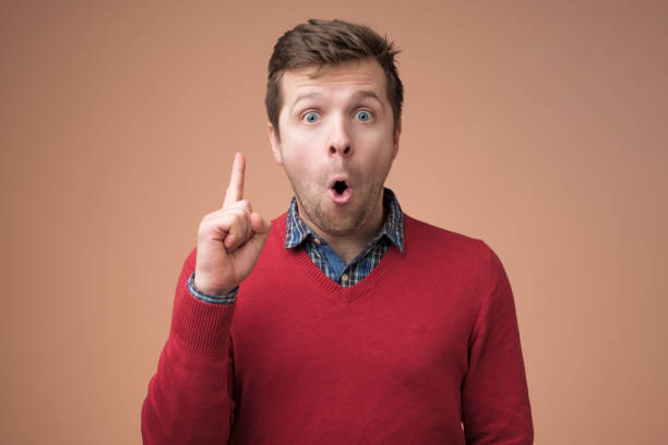istock Attractive young man in red sweater pointing up with his finger 1153645541