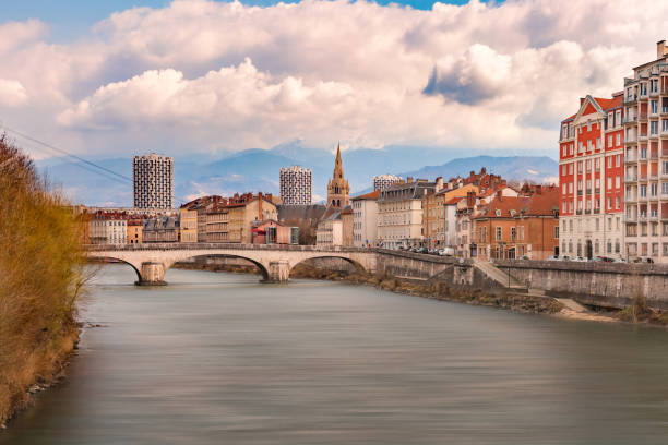 Panorama Old Town of Grenoble, France Scenic panoramic aerial view of the banks of the Isere river, bridge, roofs and French Alps on the background, Grenoble, France isere river stock pictures, royalty-free photos & images