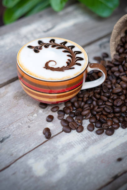 Hot Cappuccino coffee on old wooden table with roasted coffee beans.