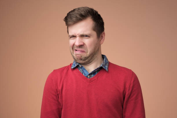 istock mature man in red sweater looking with disbelief expression 1153649917