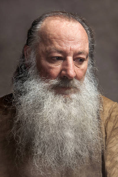 old man with a long beard with sadness on a Gray background